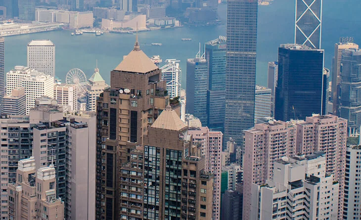 Aerial view of Hong Kong's dense skyscrapers with Victoria Harbour in the background.
